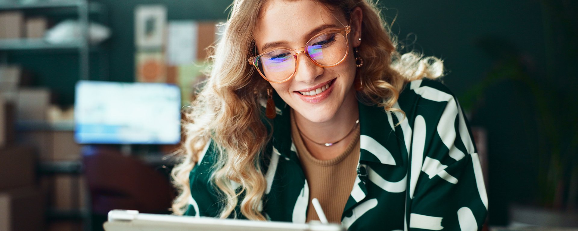 Eine lächelnde Frau mit Brille nutzt ein Tablet